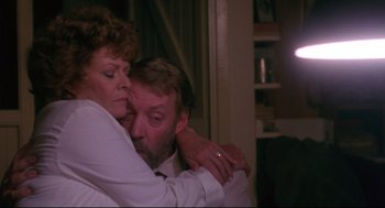 Movie still from “A Dry White Season” (1989), directed by Euzhan Palcy – A man and a woman hugging each other in front of a window; Close Up shot, Low angle