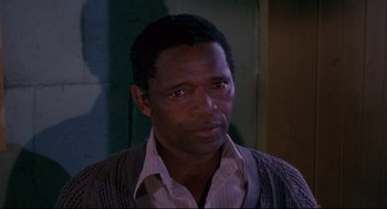 Movie still from “A Dry White Season” (1989), directed by Euzhan Palcy – A person wearing a shirt and a sweater; Close Up shot, Over the shoulder angle