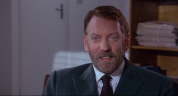 Movie still from “A Dry White Season” (1989), directed by Euzhan Palcy – A person wearing a suit and tie; Close Up shot, Over the shoulder angle