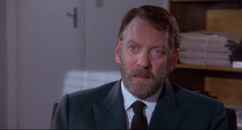 Movie still from “A Dry White Season” (1989), directed by Euzhan Palcy – A person wearing a suit and tie; Close Up shot, Over the shoulder angle