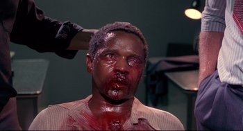 Movie still from “A Dry White Season” (1989), directed by Euzhan Palcy – A man with blood all over his face and head; Close Up shot, Over the shoulder angle