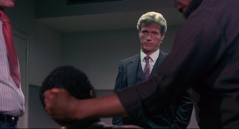 Movie still from “A Dry White Season” (1989), directed by Euzhan Palcy – A man wearing a suit and tie standing next to another man in a suit; Close Up shot, Over the shoulder angle
