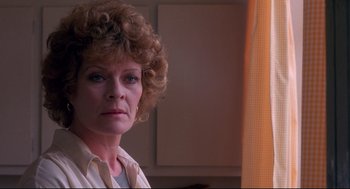 Movie still from “A Dry White Season” (1989), directed by Euzhan Palcy – An older woman with curly brown hair is looking at the camera; Close Up shot, Low angle