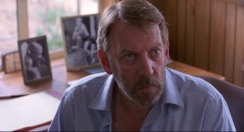Movie still from “A Dry White Season” (1989), directed by Euzhan Palcy – A person sitting at a table; Close Up shot, Over the shoulder angle