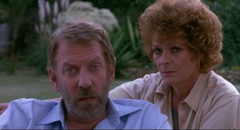 Movie still from “A Dry White Season” (1989), directed by Euzhan Palcy – An older man and a younger woman looking at the camera; Close Up shot, Over the shoulder angle