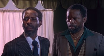 Movie still from “A Dry White Season” (1989), directed by Euzhan Palcy – Two men in suits and ties standing next to each other; Close Up shot, Low angle