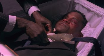 Movie still from “A Dry White Season” (1989), directed by Euzhan Palcy – A man in a suit is getting his tie pulled back; Close Up shot, High angle