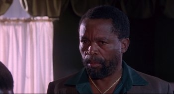 Movie still from “A Dry White Season” (1989), directed by Euzhan Palcy – An older man with a beard and a necklace; Close Up shot, Low angle