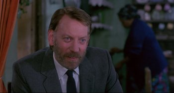 Movie still from “A Dry White Season” (1989), directed by Euzhan Palcy – A person wearing a suit and tie; Close Up shot, Over the shoulder angle