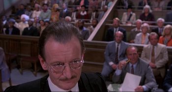 Movie still from “A Dry White Season” (1989), directed by Euzhan Palcy – A man in a suit and tie in front of an audience; Close Up shot, High angle