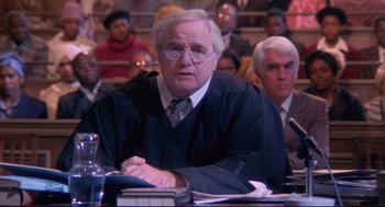 Movie still from “A Dry White Season” (1989), directed by Euzhan Palcy – An older man in a courtroom with a judge; Close Up shot, High angle