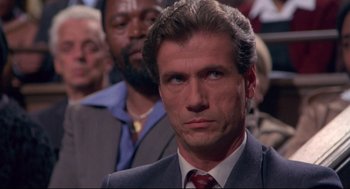 Movie still from “A Dry White Season” (1989), directed by Euzhan Palcy – A man in a suit and tie in front of a crowd; Close Up shot, High angle
