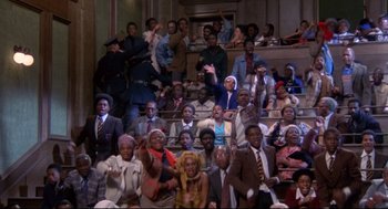 Movie still from “A Dry White Season” (1989), directed by Euzhan Palcy – A group of people sitting in a room; Extreme Wide shot, High angle