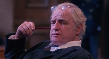 Movie still from “A Dry White Season” (1989), directed by Euzhan Palcy – An older man wearing glasses and a suit; Close Up shot, Low angle