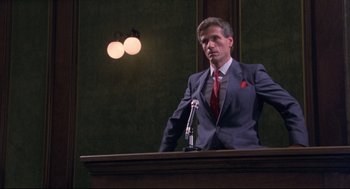 Movie still from “A Dry White Season” (1989), directed by Euzhan Palcy – A man standing at a podium with a microphone in front of him; Medium shot, Low angle