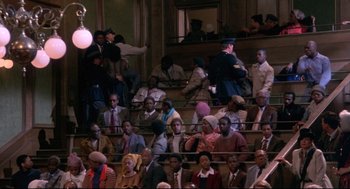 Movie still from “A Dry White Season” (1989), directed by Euzhan Palcy – A group of people sitting in a room; Extreme Wide shot, High angle