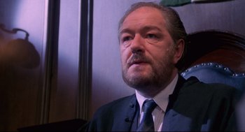 Movie still from “A Dry White Season” (1989), directed by Euzhan Palcy – An older man in a suit and tie looking to his left; Close Up shot, Low angle