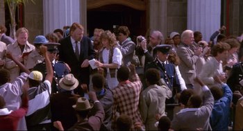 Movie still from “A Dry White Season” (1989), directed by Euzhan Palcy – A group of people standing around a building with people taking pictures; Wide shot, High angle