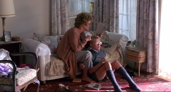 Movie still from “A Dry White Season” (1989), directed by Euzhan Palcy – A woman sitting on a couch with a boy; Wide shot, High angle