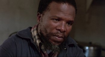 Movie still from “A Dry White Season” (1989), directed by Euzhan Palcy – A person with a beard looking at the camera; Close Up shot, Low angle