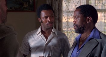 Movie still from “A Dry White Season” (1989), directed by Euzhan Palcy – Two men standing next to each other in front of a window; Close Up shot, Over the shoulder angle