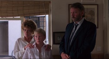 Movie still from “A Dry White Season” (1989), directed by Euzhan Palcy – A man and a woman standing next to a young boy; Medium shot, Low angle