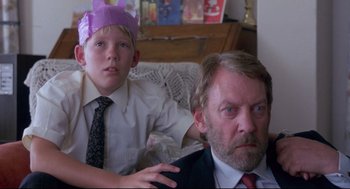 Movie still from “A Dry White Season” (1989), directed by Euzhan Palcy – A man and a boy wearing paper hats; Close Up shot, Low angle