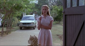Movie still from “A Dry White Season” (1989), directed by Euzhan Palcy – A woman standing next to a lion statue; Medium shot, Low angle