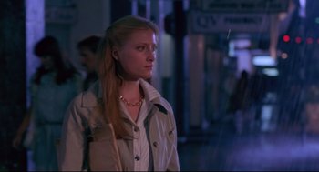 Movie still from “A Dry White Season” (1989), directed by Euzhan Palcy – A woman in a trench coat standing on a sidewalk; Medium shot, Low angle