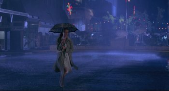 Movie still from “A Dry White Season” (1989), directed by Euzhan Palcy – A woman walking down a street holding an umbrella; Wide shot, Low angle