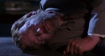 Movie still from “A Dry White Season” (1989), directed by Euzhan Palcy – A man with a beard is laying on the ground; Close Up shot, Overhead angle