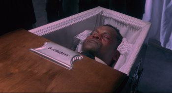 Movie still from “A Dry White Season” (1989), directed by Euzhan Palcy – A man in a casket with his eyes closed; Close Up shot, High angle