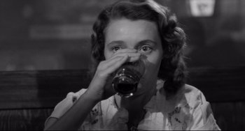 Movie still from “A Face in the Crowd” (1957), directed by Elia Kazan – A black and white photo of a woman drinking a glass of wine; Close Up shot, High angle