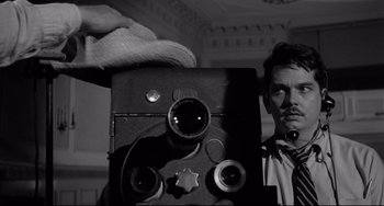 Movie still from “A Face in the Crowd” (1957), directed by Elia Kazan – A black and white photo of a man holding a camera; Close Up shot, Low angle