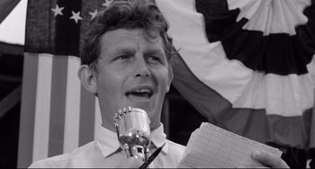 Movie still from “A Face in the Crowd” (1957), directed by Elia Kazan – A man is holding a microphone in front of an american flag; Close Up shot, Low angle