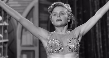 Movie still from “A Face in the Crowd” (1957), directed by Elia Kazan – A woman in a sequined bra is raising her arms; Close Up shot, Low angle