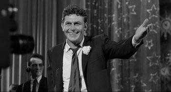 Black and white photograph of a man in a suit waving