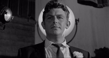 Movie still from “A Face in the Crowd” (1957), directed by Elia Kazan – Black and white photograph of a man wearing a suit and tie; Close Up shot, Low angle
