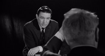 Movie still from “A Face in the Crowd” (1957), directed by Elia Kazan – A black and white photo of a man in a suit and tie; Close Up shot, Over the shoulder angle