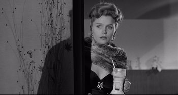Movie still from “A Face in the Crowd” (1957), directed by Elia Kazan – A black and white photo of a woman holding a drink; Close Up shot, Over the shoulder angle