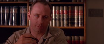 Movie still from “A Few Good Men” (1992), directed by Rob Reiner – A person sitting in front of a book shelf; Close Up shot, Low angle