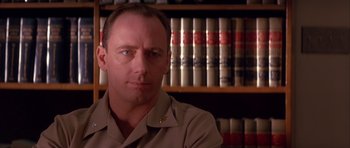Movie still from “A Few Good Men” (1992), directed by Rob Reiner – A person sitting in front of a book shelf; Close Up shot, Low angle