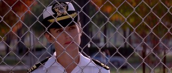 Movie still from “A Few Good Men” (1992), directed by Rob Reiner – A woman in a military uniform standing in front of a chain link fence; Close Up shot, Over the shoulder angle