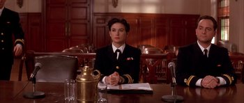 Movie still from “A Few Good Men” (1992), directed by Rob Reiner – A woman sitting at a table in front of a microphone; Medium shot, Low angle