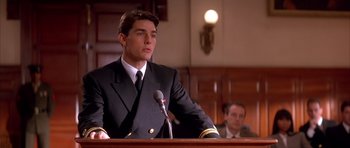 Movie still from “A Few Good Men” (1992), directed by Rob Reiner – A man wearing a suit and tie sitting at a podium; Medium shot, Low angle