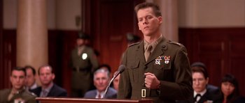 Movie still from “A Few Good Men” (1992), directed by Rob Reiner – A man in a military uniform standing at a podium with microphones; Close Up shot, Low angle