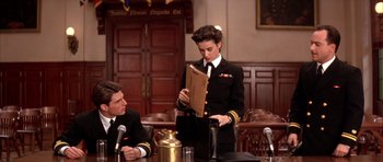 Movie still from “A Few Good Men” (1992), directed by Rob Reiner – A woman in a military uniform holding a clipboard in a courtroom; Medium shot, Low angle