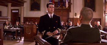 Movie still from “A Few Good Men” (1992), directed by Rob Reiner – A man in a military uniform holding a laptop in a courtroom; Medium shot, Over the shoulder angle