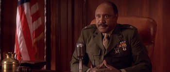 Movie still from “A Few Good Men” (1992), directed by Rob Reiner – A man in a uniform sitting in front of a microphone; Medium shot, Low angle
