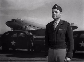 Movie still from “A Foreign Affair” (1948), directed by Billy Wilder – A man in a military uniform standing in front of an airplane; Medium shot, Low angle